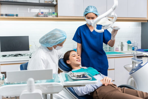 Caucasian dentist examine tooth for young girl at dental health clinic. Attractive woman patient lying on dental chair get dental treatment from doctor during procedure appointment service in hospital