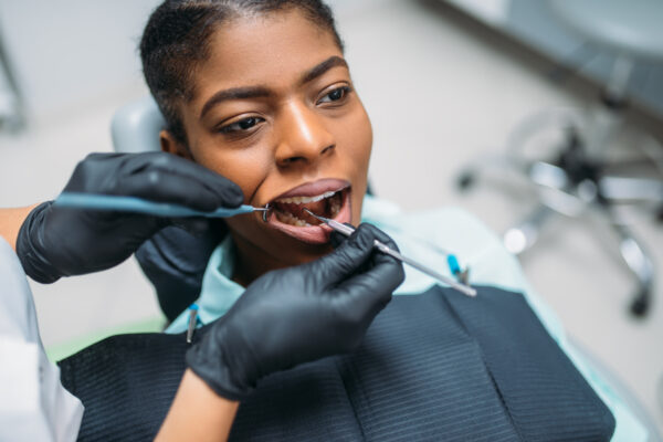 Dentist examines the teeth of female patient in dental clinic. Woman in dentistry cabinet, stomatology