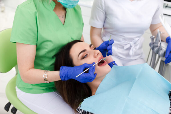 Dentist and assistant treat patient teeth. Girl examined at the dentist